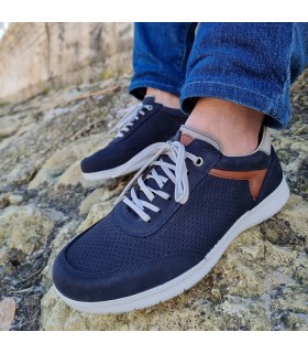 Zapato hombre cordones nobuck azul puestas en los pies posando junto al mar