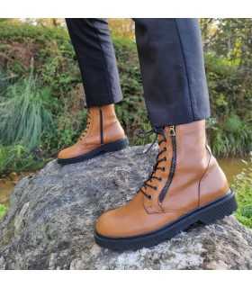 Botas estilo militar waterdrops camel de Rizzoli, vista lateral en modelo posando sobre una roca