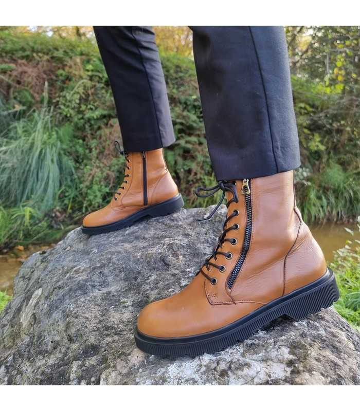 Botas estilo militar waterdrops camel de Rizzoli, vista lateral en modelo posando sobre una roca