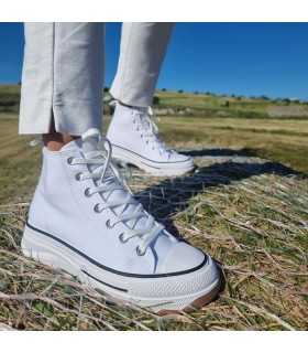 Bota sneaker plataforma lona blanca mujeren mujer posando sobre una paca de paja