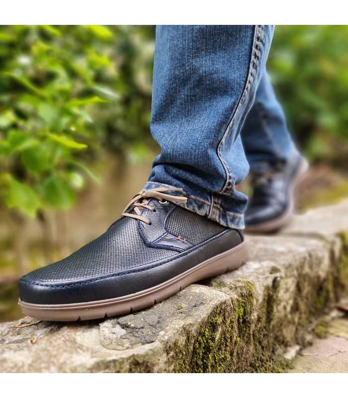 Zapato sport de cordones punteado de Luisetti de piel azul marino puesto en un hombre con vaqueros