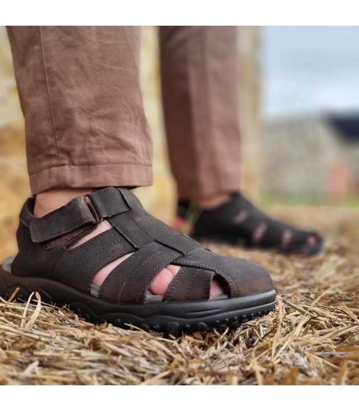 Vista de perfil las sandalias puestas en un hombre sobre una paca de heno