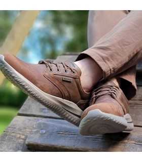 Zapatos Skechers Glavine marrón puestos en un parque con pantalones marrones, cómodo para invierno.