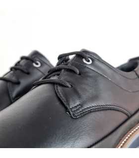 Detalle del cierre con cordones, que asegura un ajuste cómodo y seguro en zapato negro