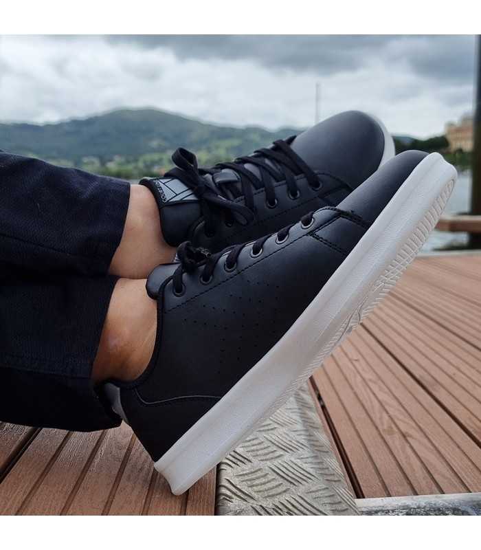Zapatilla deportiva Court Trainers puestas en modelo con los pies cruzados.
