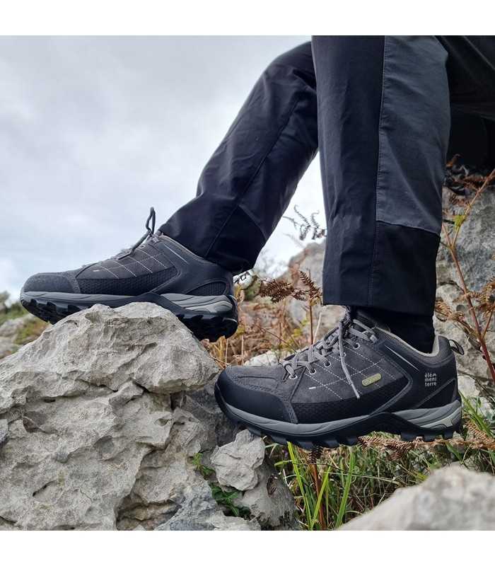 Zapatilla de senderismo Sonora gris de Elementerre en modelo puestas sobre las rocas