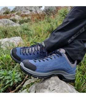 Modelo posando con los pies cruzados con las Zapatillas de trekking piel de Grisport para hombre azules puestas