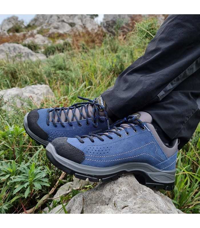 Modelo posando con los pies cruzados con las Zapatillas de trekking piel de Grisport para hombre azules puestas
