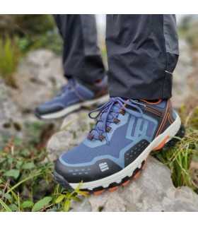 modelo posando sobre una roca con las Zapatillas de senderismo Hedley azul de Elementere