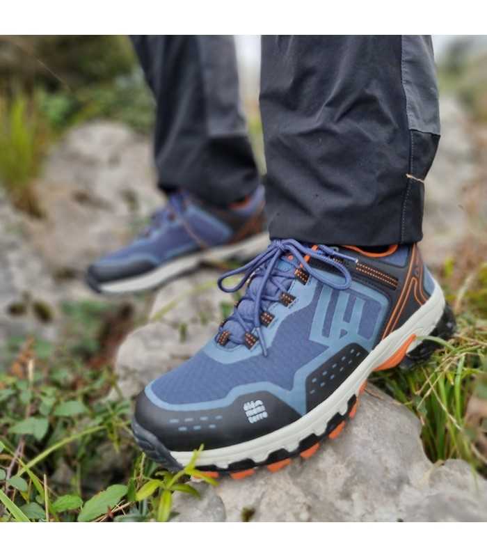 modelo posando sobre una roca con las Zapatillas de senderismo Hedley azul de Elementere