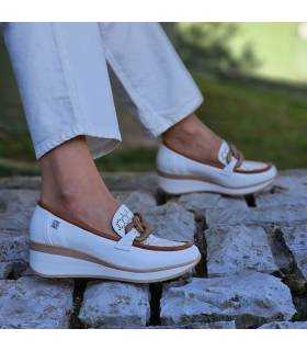 Zapatos de mujer mocasín con cuña de piel blanca puestos en una mujer