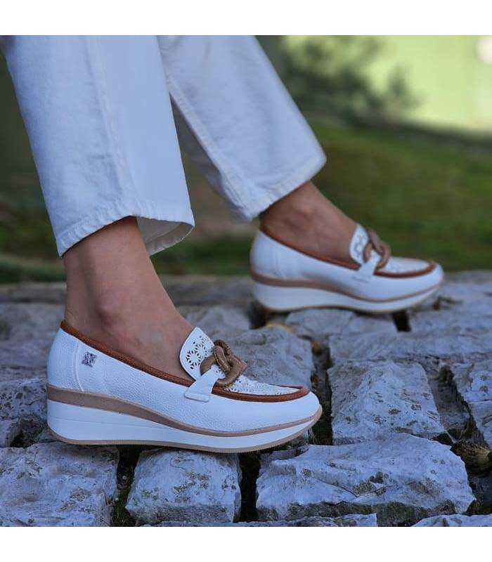 Zapatos de mujer mocasín con cuña de piel blanca puestos en una mujer