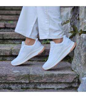 Deportivo mujer blanco Skechers  combinado con pantalón blanco puesto en modelo posando de puntillas