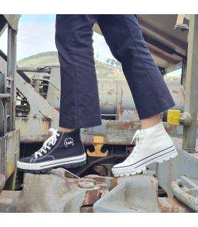 Bota de lona deportiva blanca y negra, una puesta en cada pié.