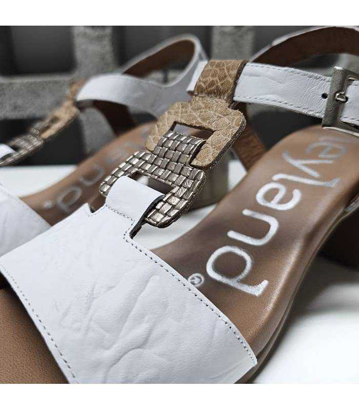 Detalle de piel blanca combinada con texturas metalizadas en sandalia de tacón Suave