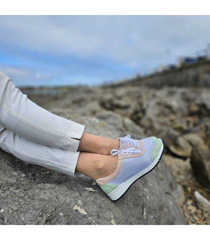 Pies cruzados sobre rocas posando en una modelo con los zapatos de cordones blancos de Suave by Leyland