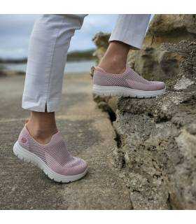 Subiendo unas rocas , vistos de perfil los deportivos rosas de mujer puestos en la modelo