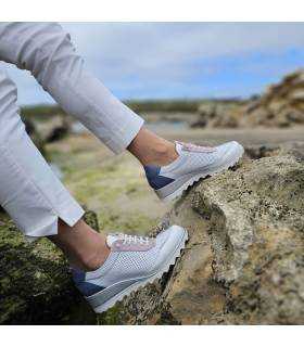 mujer posando sobre unas rocas junto al mar con los zapatos deportivos blancos de DChicas