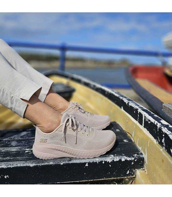 modelo posando con los deportivos beige Bobs Squad de Skechers en el banquillo de una barca