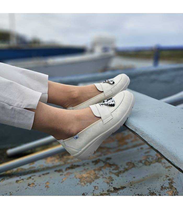 Vista lateral de los zapatos mocasines color vainilla puestos en modelo
