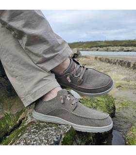 Pies cruzados de un hombre en una roca posando con los zapatos deportivos Melson beige de Skechers