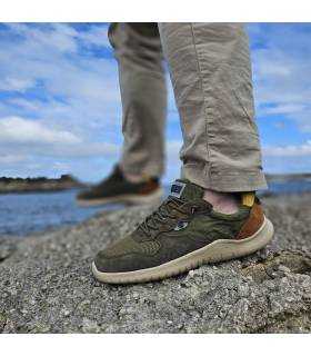 Zapatillas hombre piel textil verde Coronel Tapioca puestas sobre rocas junto al mar, estilo casual para verano puestas