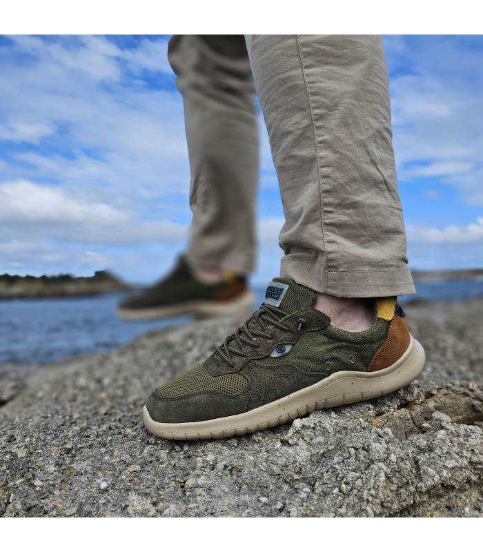 Zapatillas hombre piel textil verde Coronel Tapioca puestas sobre rocas junto al mar, estilo casual para verano puestas