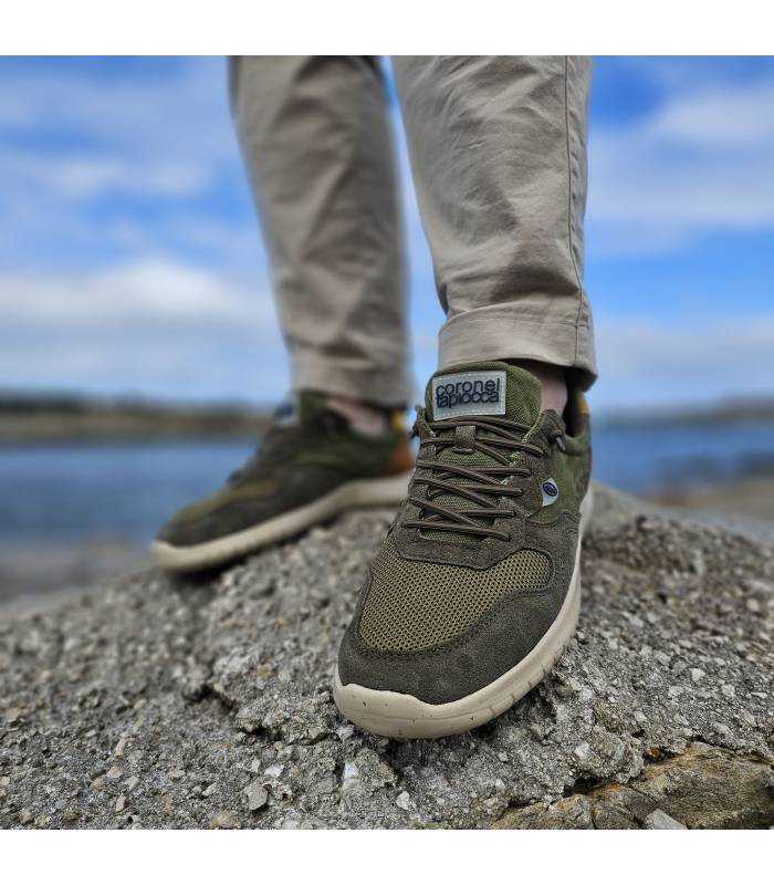 Zapatillas hombre piel textil verde Coronel Tapioca puestas sobre rocas junto al mar, estilo casual para verano