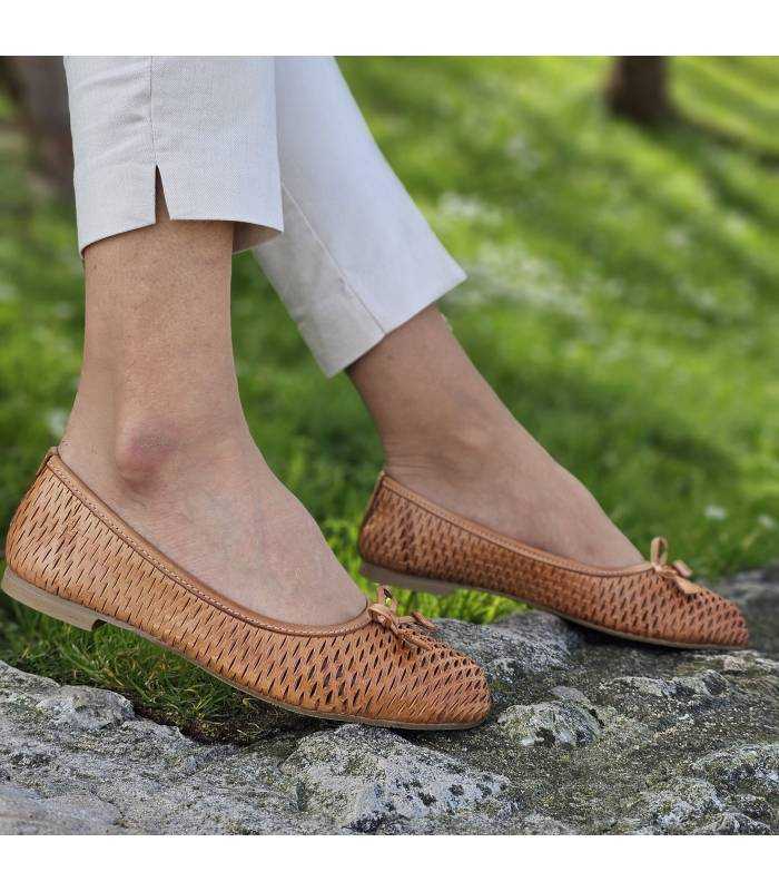 zapato bailarina de mujer de piel calada puesto en modelo posando en el jardín