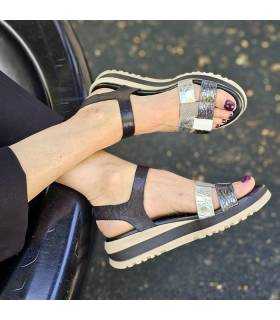 pies cruzados de mujer con las sandalias con plataforma en piel combinada negra y plata