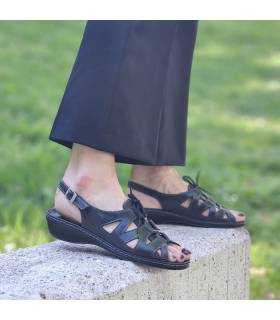 Vista lateral de sandalia de piel negra con cordones puesta en modelo