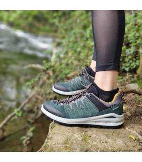 Vista de perfil de zapatillas de trekking verde puesto en una modelo junto al rio