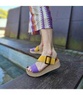 modelo posando con las sandalias de piel moradas y amarillas con vestido veraniego