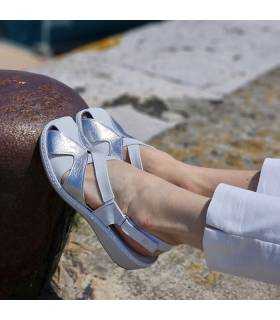 Modelo posando en un noray con las sandalias de piel blancas cerradas adelante