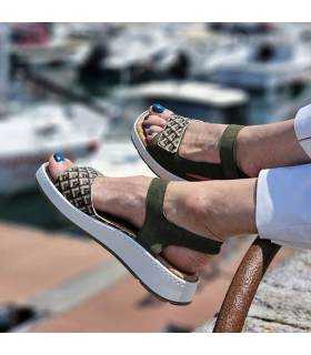 sandalia verde con cierre de velcro y plantilla extraible puesta en modelo posando junto a barcos