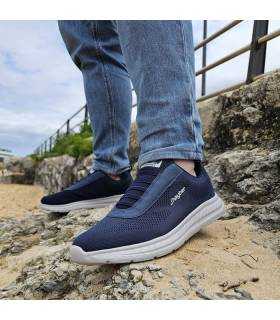 zapatilla deportiva azul marino con cordones elásticos d e verano posando modelo junto a la plya