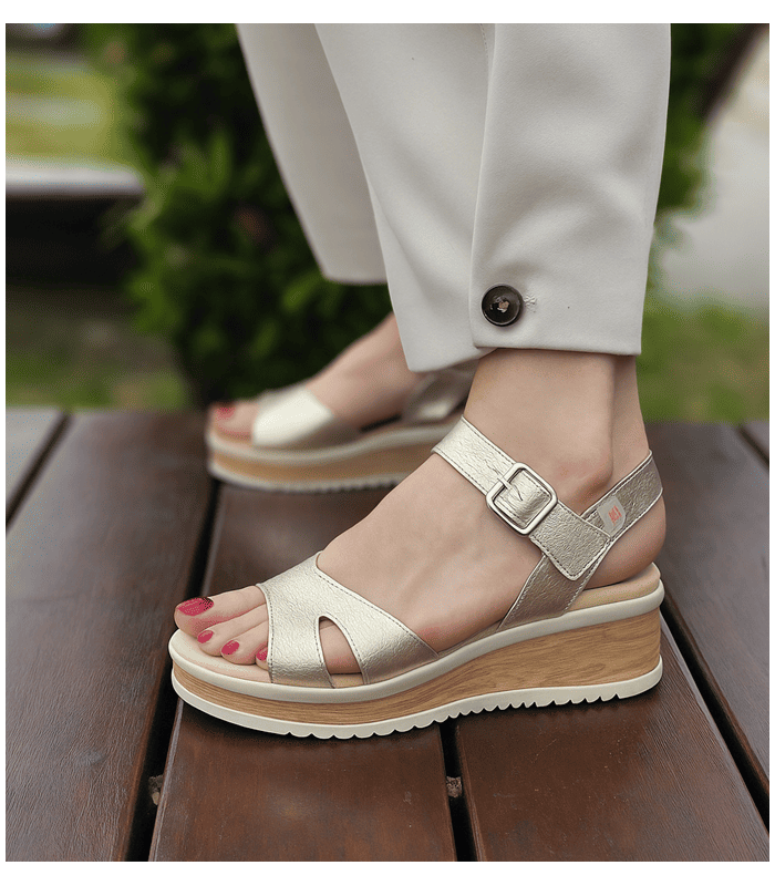 mujer posando con las sandalias doradas con cuña de pepe Saenz