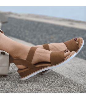 modelo con los pies cruzados con la sandalia marrón de Skechers