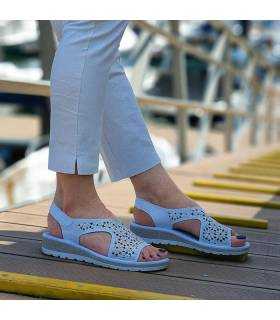 Sandalias blancas del Doctor Cutillas puestas en modelo junto a un atracadero de barcos puestas