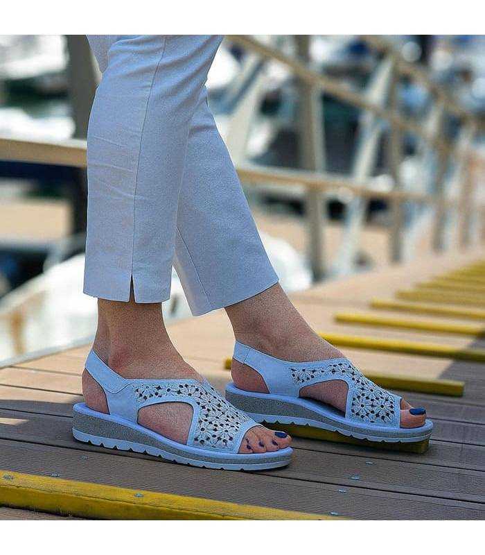 Sandalias blancas del Doctor Cutillas puestas en modelo junto a un atracadero de barcos puestas