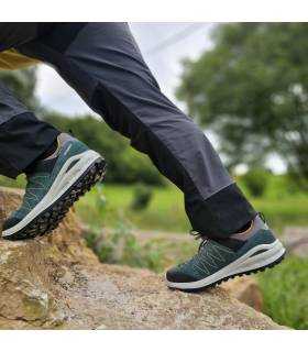hombre trepando sobre una roca con la zapatilla unisex verde de Grisport
