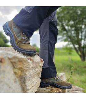 hobre caminando sobre rocas con las botas de senderismo verdes de Postigo