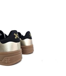 Parte trasera de zapatillas XTI beige nacarado para mujer con plataforma y talón negro con logo.