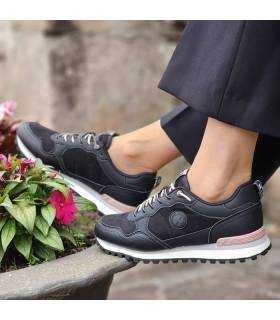 mujer posando con las zapatillas casul negras de XTI