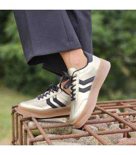 mujer posando con las zapatillas doradas de Xti