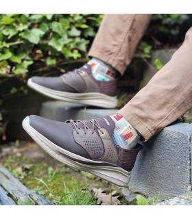 hombre posando con las zapatillas marrones de Skechers puestas en unas escaleras