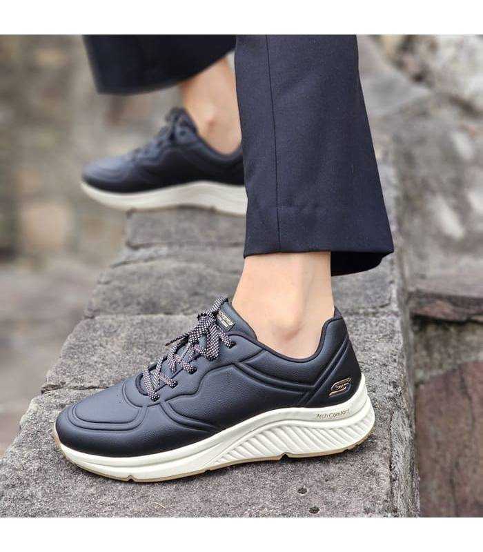 mujer posando lcon las zapatillas depotivas negras de Skechers