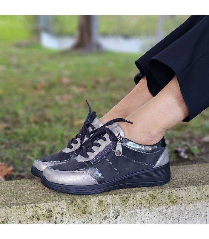 Zapatos deportivos MySoft color negro puestos, con pantalón oscuro, sobre base de piedra al aire libre.