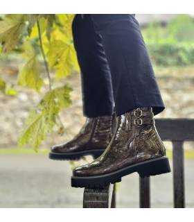 Botines de mujer estilo militar marrones de piel puestas en modelo posando en la barandeilla de un banco