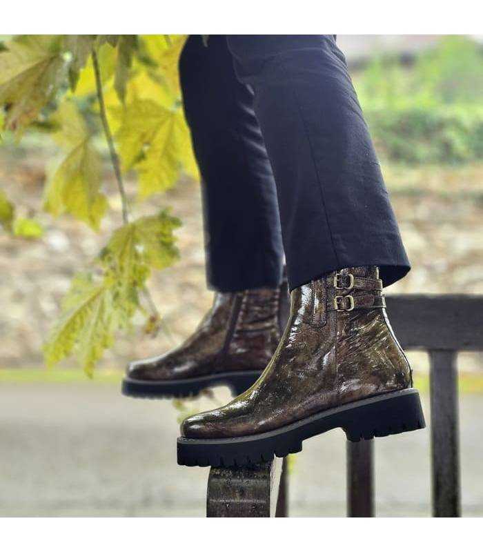 Botines de mujer estilo militar marrones de piel puestas en modelo posando en la barandeilla de un banco